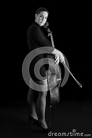 Beautiful brunette playing cello with selective light in black d Stock Photo