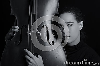 Beautiful brunette playing a cello with selective light in black Stock Photo