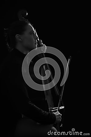 Beautiful brunette playing a cello with selective light in black Stock Photo