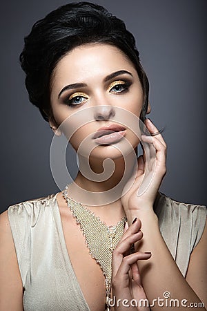 Beautiful brunette woman with perfect skin, gold makeup and handmade jewelry. Beauty face. Stock Photo