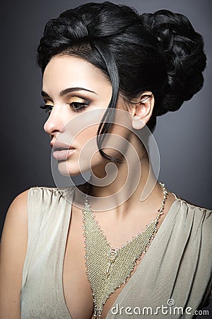 Beautiful brunette woman with perfect skin, gold makeup and handmade jewelry. Beauty face. Stock Photo