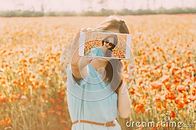 Woman taking selfie with smartphone in flowers field. Stock Photo