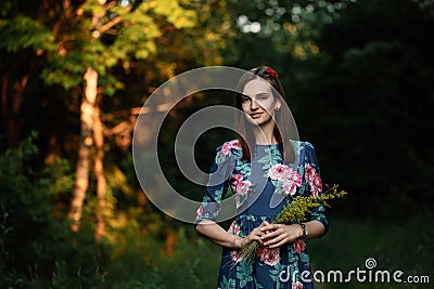 Beautiful brunette young woman wearing dress and walking on the forest. Flare for text and design. Lifestyle in the city Stock Photo