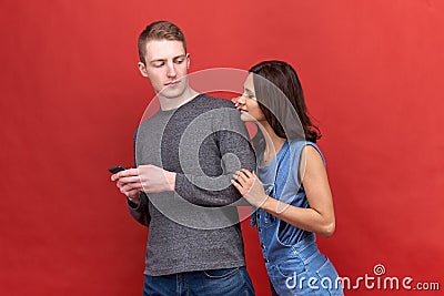 Beautiful burning brunette woman stares incredulously spying to phone her boyfriend Stock Photo