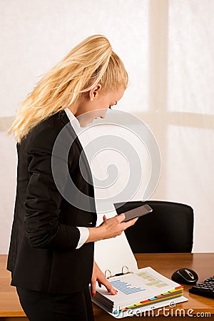 Beautiful business woamn talks on smart phona and holds a folder in her office Stock Photo