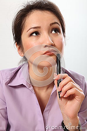 Beautiful business woman deep in thought with pen Stock Photo