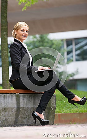 Beautiful business woman working with laptop in park Stock Photo