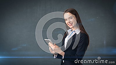 Beautiful businesswoman is looking into a touch pad and smiling, gray background Stock Photo