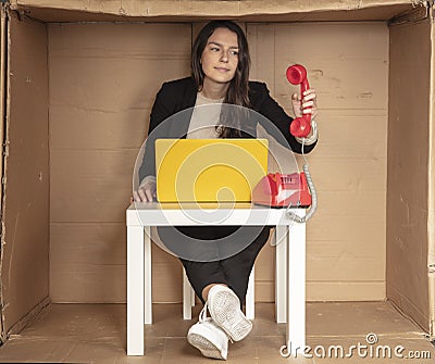 Beautiful businesswoman sits in a cramped paper office, picks up the phone Stock Photo