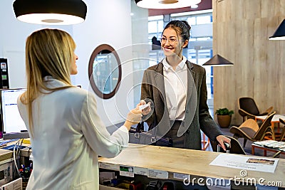 Beautiful businesswoman takes room key card and doing check-in at the hotel reception Stock Photo
