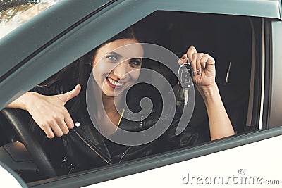 Beautiful car driver woman smiling showing new car keys and car. Caucasian girl sitting in automobile, smiling and Stock Photo