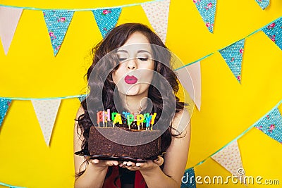 Beautiful caucasian girl blowing candles on her cake. Celebration and party. Having fun. Young pretty woman in red dress and birth Stock Photo