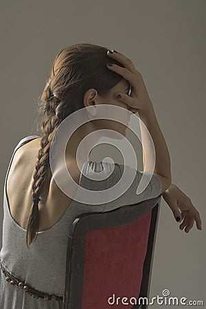 Beautiful caucasian girl slouching on chair - gray background with copy space Stock Photo