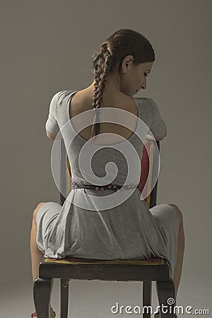 Beautiful caucasian girl slouching on chair - gray background with copy space Stock Photo