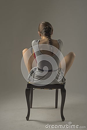 Beautiful caucasian girl slouching on chair - gray background with copy space Stock Photo