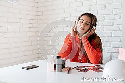 Beautiful caucasian nail master having reast on the workplace listening to the music Stock Photo