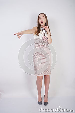 Beautiful caucasian teen girl stands in a short evening dress and mocks the interlocutor, humiliating, on a white background in th Stock Photo