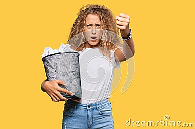 Beautiful caucasian teenager girl holding paper bin full of crumpled papers annoyed and frustrated shouting with anger, yelling Stock Photo