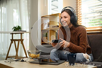 Beautiful caucasian woman in headset holding joystick playing video game at home Stock Photo