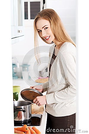 Beautiful caucasian woman standing in kitchen and cooking. Stock Photo