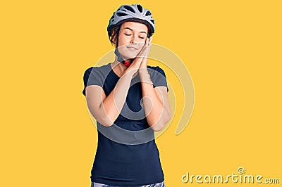 Beautiful caucasian woman wearing bike helmet sleeping tired dreaming and posing with hands together while smiling with closed Stock Photo