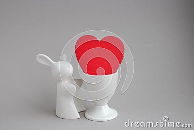 Beautiful ceramic rabbit on white background. statuette of a white rabbit with a red heart.Easter decor Stock Photo