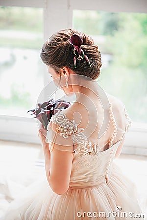 Beautiful charming bride in a luxurious dress looking up.Portrait Of Happy Bride Sitting in wedding dress in a white photo Stock Photo