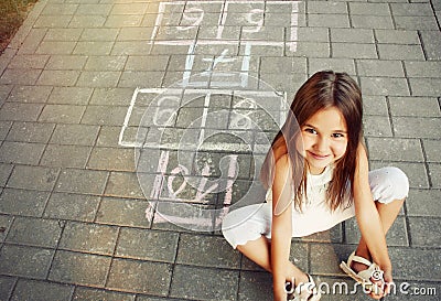 Beautiful cheerful little girl playing hopscotch on playground Stock Photo