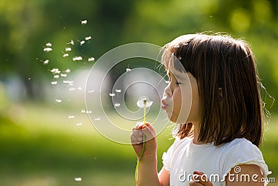 Beautiful child with dandelion flower in spring park. Happy kid having fun outdoors. Stock Photo