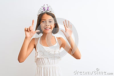 Beautiful child girl wearing princess crown standing over isolated white background showing and pointing up with fingers number Stock Photo