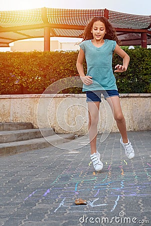 Girl playing hopscotch game on the asphalt on playground. Stock Photo