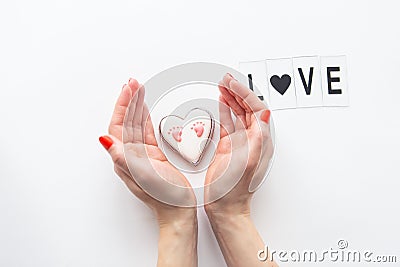 Beautiful children`s footprint in the shape of a heart, the girl`s hands hug the heart. Love lettering Stock Photo