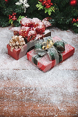 Beautiful Christmas and new year gift boxes on wooden board, pine branches with ornaments background. Motion of snow falling and Stock Photo