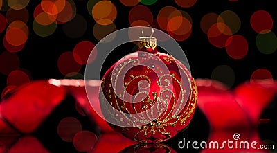 Beautiful Christmas toy is decorated with a gold pattern and rhinestones, on shimmering dark red Stock Photo