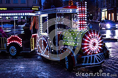 A beautiful Christmas train shines with bright lights and pleases many children. Editorial Stock Photo