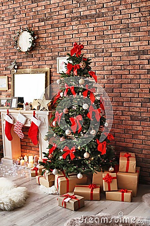 Beautiful Christmas tree and gifts near fireplace with stockings indoors Stock Photo