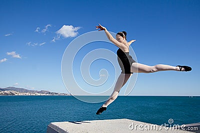 Beautiful classic dancer jumping over a big stone block. Stock Photo