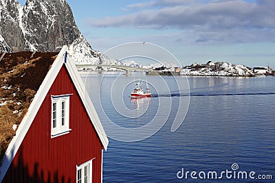 Beautiful classical view of winter fjord with red house and fishing boat in Olenilsoya in Reine, Lofoten Islands, Norway Stock Photo