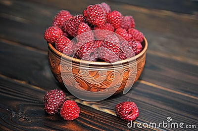 A beautiful clay pot with raspberries on a wooden table. raspberries in a plate. Stock Photo