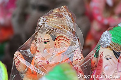 A Beautiful clay statue/Idol of an Indian god Lord Ganesha decorated with colorful drapery and Marigold garland Stock Photo