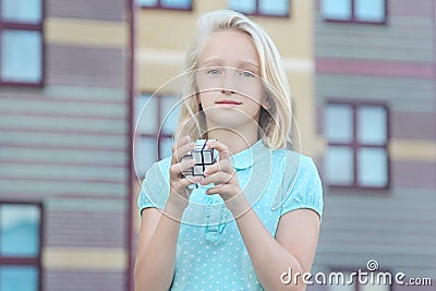 Beautiful and clever blonde kid girl solves a mirror cube puzzle Stock Photo