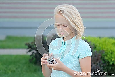 Beautiful and clever blonde kid girl solves a mirror cube puzzle Stock Photo