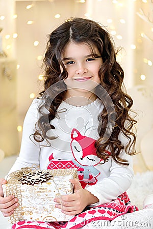 Beautiful close up portraite of curly girl with gold Christmas garlands magic lights and tree decorations gift box Stock Photo