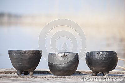 Beautiful closeup of three unique planters of black pottery in summer morning sunlight Stock Photo