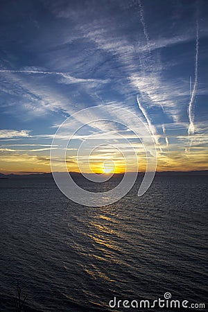 CLOUDS AND CONTRAILS IN THE SUNSET Stock Photo