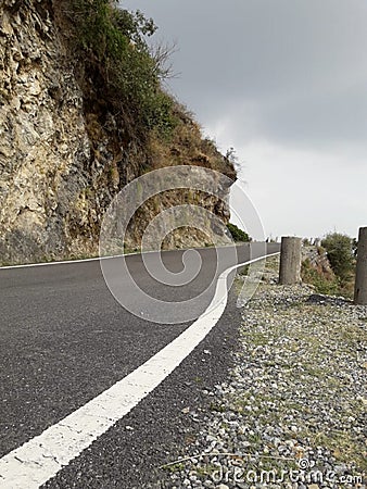 Beautiful cloudy road seen between hills Stock Photo