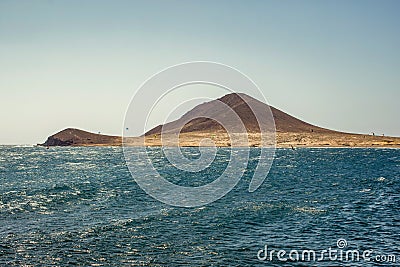 Beautiful coastal view of Montana Roja - Red Mountain. Shining clear blue sky over Horizon line, wave ripples on the turquoise Stock Photo