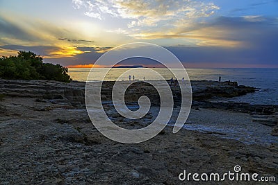 Group of people on edge watching beautiful colorful sunset at the sea with dramatic clouds and sun shining. Beauty world Editorial Stock Photo