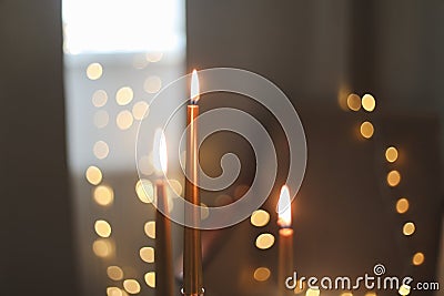 Beautiful composition with burning wax candles on table. Elegant golden candlesticks with burning candles in a cozy room Stock Photo