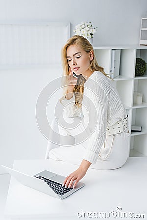 beautiful concentrated businesswoman in white clothes working with laptop Stock Photo